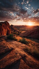 Naklejka premium Dramatic sunset over a rocky desert landscape with warm light illuminating the terrain