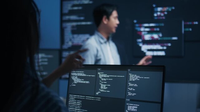Male software engineer presenting a Coding Task, AI chatbot workflow with code on multiple monitors in a modern office. coding collaboration and agile projects Concept.