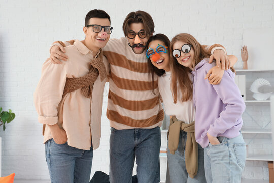 Business colleagues with funny disguise hugging in office. April Fools' Day celebration