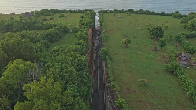 Drone flying backward revealing Tanah Barak cliffs, Indonesia