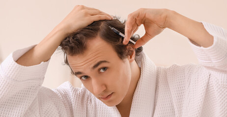 Naklejka premium Young man with hair loss problem making injection in bathroom, closeup