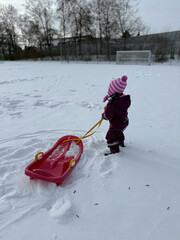 A little pretty girl plays with sleds in winter in nature. 