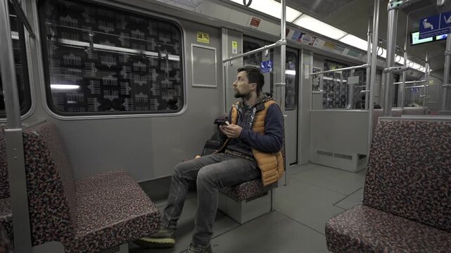Man takes subway in Berlin, Germany and using smartphone. Male with smart phone on commuter train. Passenger on Berlin subway surfing internet on phone. Fahrgast in der U-Bahn in Berlin, Deutschland. 