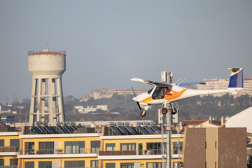 Light aircraft flying low over urban buildings and solar panels