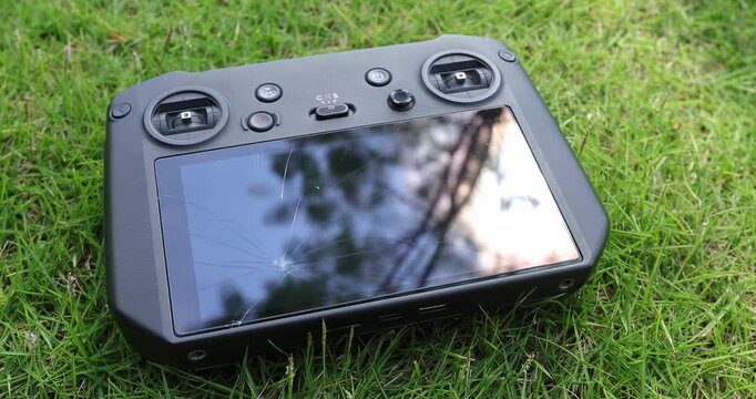 Broken drone remote controller on the green grass