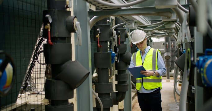 Professional industrial engineer is inspecting pipeline machinery in a modern facility, focusing on structural safety, strict quality control and optimizing daily operations.