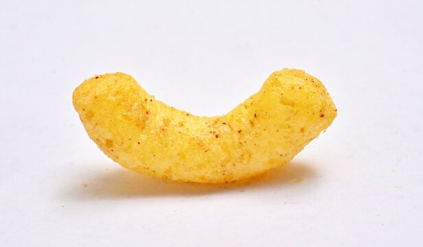 Close-up of a single curved, seasoned yellow corn puff on white background.