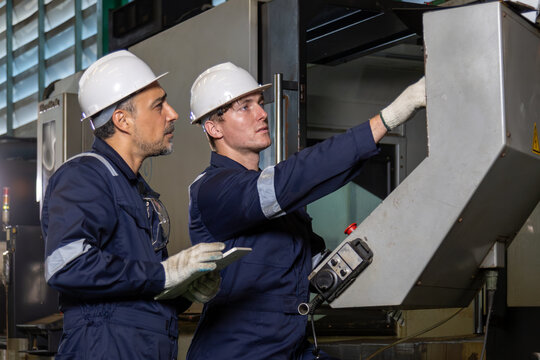Car Factory: Project Manager and Automotive Engineer in Hard Hat, Talking, Using Laptop. Monitoring, Control, Equipment Production. or control operate CNC machine in heavy industry metal factory.