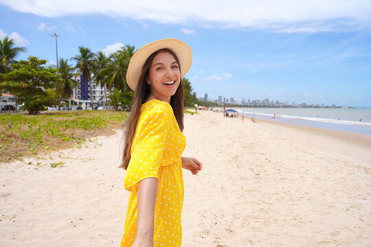Young woman with yellow sundress walking on Cabo Branco beach, Joao Pessoa, Brazil