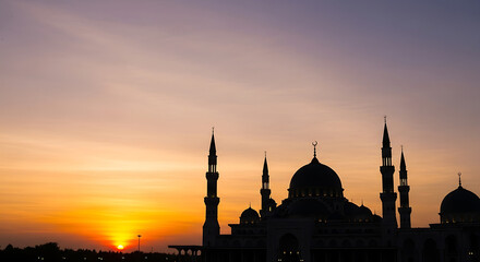 Silhouette of mosque at vibrant sunset with minarets and domes © ASAD