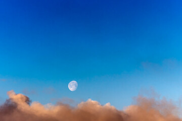 Obraz premium Full Moon in Clear Blue Sky Above Golden Sunset Clouds