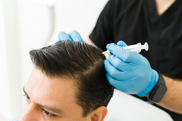 Man receiving hair restoration treatment on scalp at a dermatology clinic for hair loss and regrowth