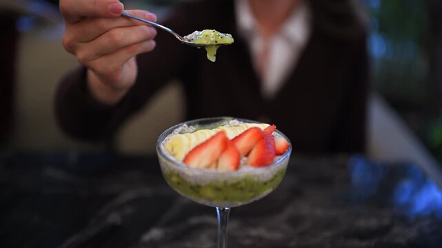 Close up of a chia pudding dessert served in a glass, topped with sliced strawberries and fruit puree