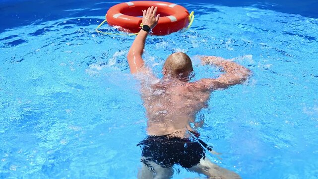 Drowning person uses life preserver by grabbing it.Training exercise for rescuers using simulated emergency situations with swimming equipment and victims. Concept: Water safety, drowning