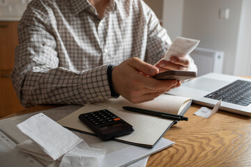 Man at home kitchen calculate and planning family financial budget. Stressful situation with unpaid bills and expensive household.