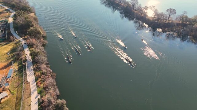 Vertical drone perspective capturing synchronized rowing teams moving across Lady Bird Lake in Austin, Texas. 