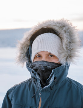 Snow-covered landscapes surround a visitor bundled in warm clothing, showcasing the enchanting atmosphere of Akaslompolo Village in Lapland, Finland 