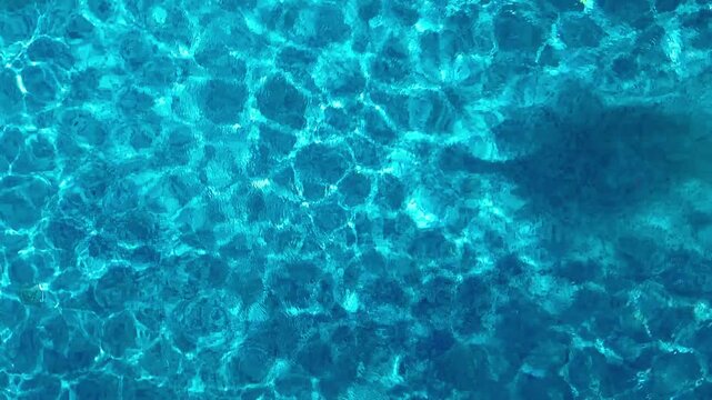Aerial view of young woman in hat relaxing in swimming pool, beautiful girl in bikini floats on inflatable ring donut and has fun in water, tropical vacation on holiday resort, top drone view
