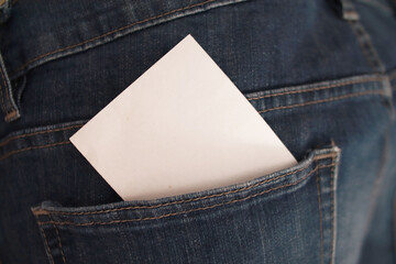 Blank white paper tucked in a denim jeans pocket, close-up with copy space