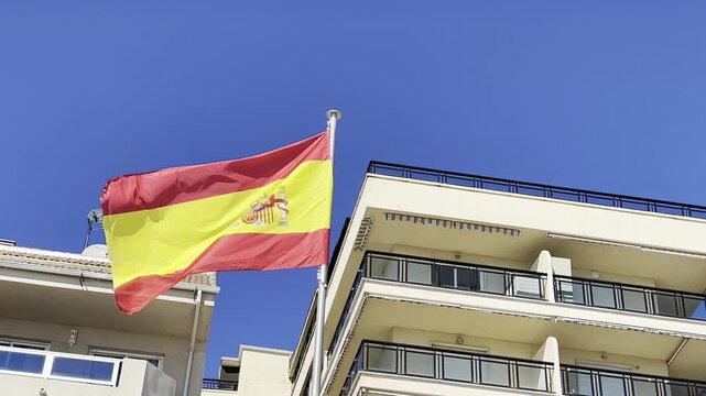Spanish flag waving on flagpole in sunny sky