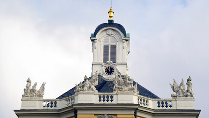 Fototapeta premium Bright yellow castle in Europe surrounded by fresh spring greenery and blooming trees. Soft daylight highlights the historic architecture and warm facade colors. Peaceful seasonal atmosphere makes the