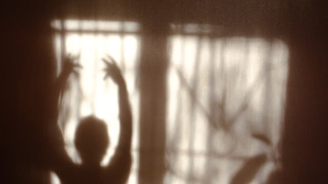 Shadow of happy young dancing lady. Listening music, repetition. Silhouette. She dancing  letting her body move freely. Charm impressed girl. Performance, choreography