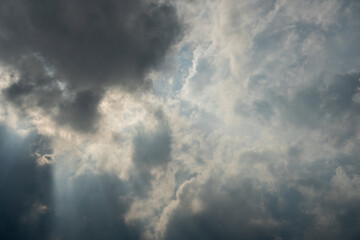 Fototapeta premium Dark gray storm clouds with bright sunbeams breaking through
