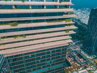 Eco friendly skyscraper with green balconies and modern architecture in Ho Chi Minh City, Sustainable highrise tower with greenery terraces and glass facade in Saigon urban skyline