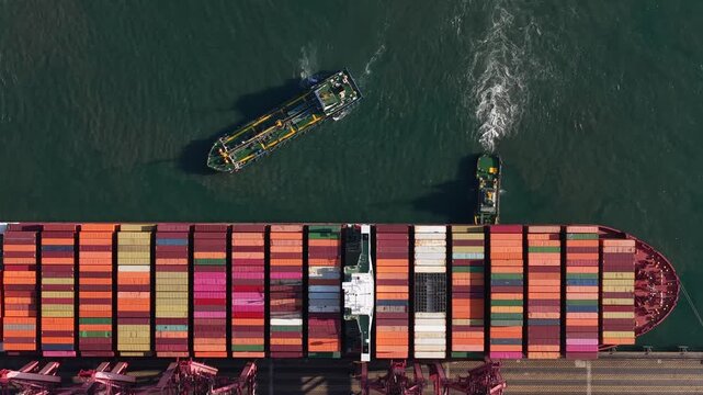 Aerial top down view of container ship docking at port terminal
