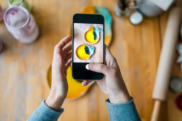 Hands of a woman photographing her products with a smartphone in a ceramics studio