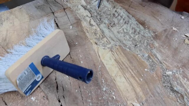 A carpenter in overalls chiselling a wooden slab in a carpentry workshop. A working man. Tools, chisel, mallet. Woodworking. Sawdust, wood chips. Real people. Lifestyle, Authentic, Candid
