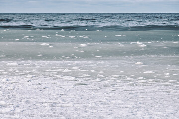 Winter sea with slush ice floating on cold water under cloudy sky © TRAVELARIUM
