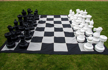 oversized outdoor Chess set arranged on a large black and white checkered mat placed on grass © Steve travelguide