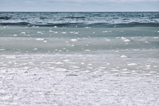 Winter sea with slush ice floating on cold water under cloudy sky