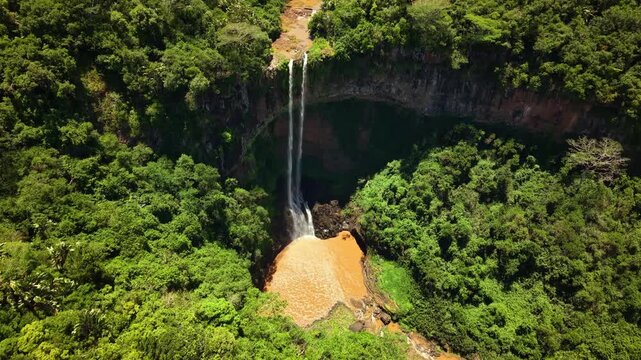 Aerial view of magnificent Chamarel Waterfall cascading into emerald pool with rainbow forming in tropical Mauritius rainforest landscape