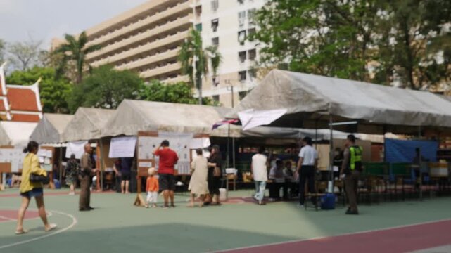 Blurred outdoor voting polling station area with tent booths tables for Thailand election day community participation background