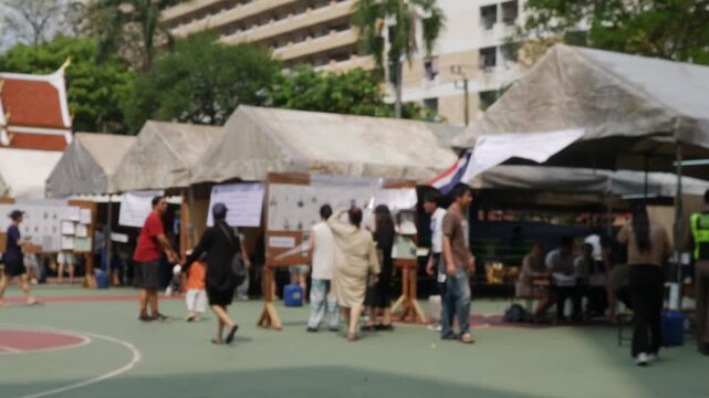 Blurred outdoor voting polling station area with tent booths tables for Thailand election day community participation background