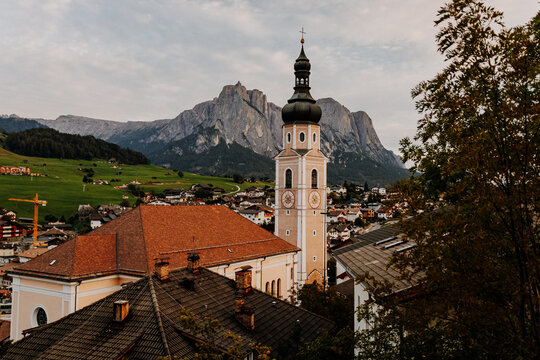 Ancient religious frescoes on the exterior wall of St. Valentin church with wooden benches, South Tyrol, Italy