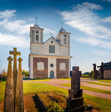 Wonderful summer view of Catholic John the Baptist Church with three wooden sculptures. Picturesque morning scene of Vainutas town, Silute District, Lithuania, Europe. Traveling concept background.
