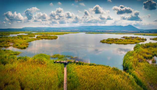 Attractive summer view from flying drone of Riserva Naturale Statale Lago di Lesina (Sacca Orientale) - nature preserve with old wooden pier. Superb morning scene of Italy, Europe.