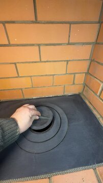 A stove master demonstrates the cooktop of a newly built heating stove. Removes the burner rings and puts them back in place. Vertical video.