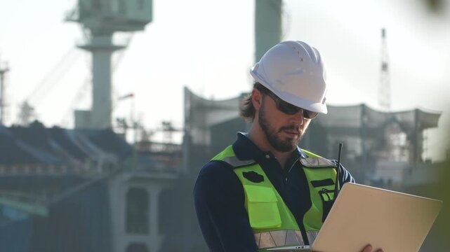 Civil engineering contractor executing site surveying protocols with specialized software. Project manager reviewing architectural blueprints at heavy construction zone.