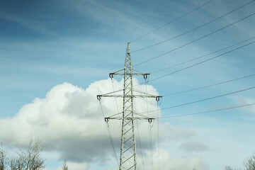 Electricity tower stands against a cloudy sky during the day in an open area