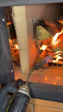 A stove master lights the firewood in the stove firebox using a gas torch. Checks the operation of the newly built stove. Construction of a heating stove. Vertical video.