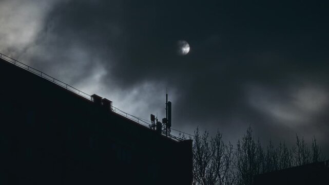 Nighttime Urban Scene Showing Antenna With Moonlight And Storm Clouds Creating Moody Atmosphere