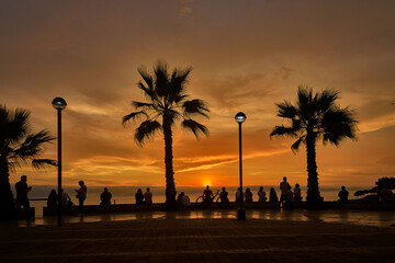 Obraz premium Romantic couples and retired travelers enjoying a vibrant summer sunset along the Malecón in Miraflores, Lima, Peru, capturing an active coastal lifestyle, scenic ocean views, and relaxed urban leisur