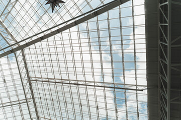 Modern glass roof architecture with metal grid and blue sky