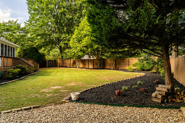 Landscaped suburban backyard with green lawn and wooden fence © Trey