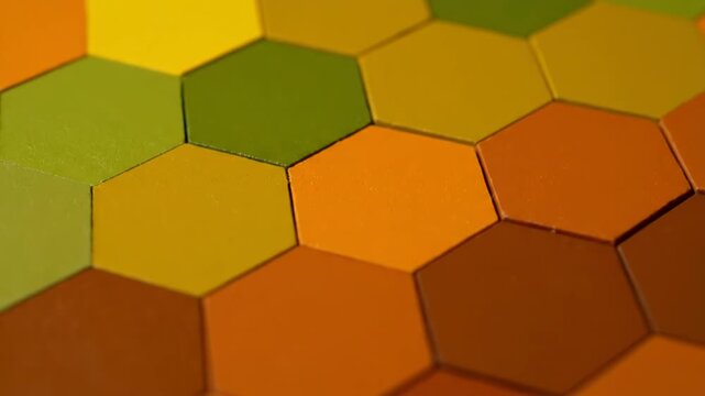 A vibrant mosaic of interlocking hexagonal shapes creates a warm, textured background. The geometric pattern features a rich palette of earthy autumn colors.