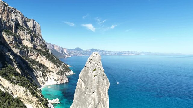 Aerial view of Punta Caroddi at Cala Goloritz&egrave;, Baunei coast, Sardinia, Italy. Iconic limestone pinnacle rising above turquoise Mediterranean waters on a sunny day.